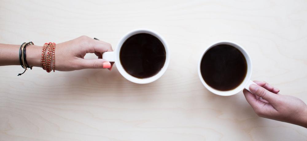 två händer som håller i varsin kaffekopp